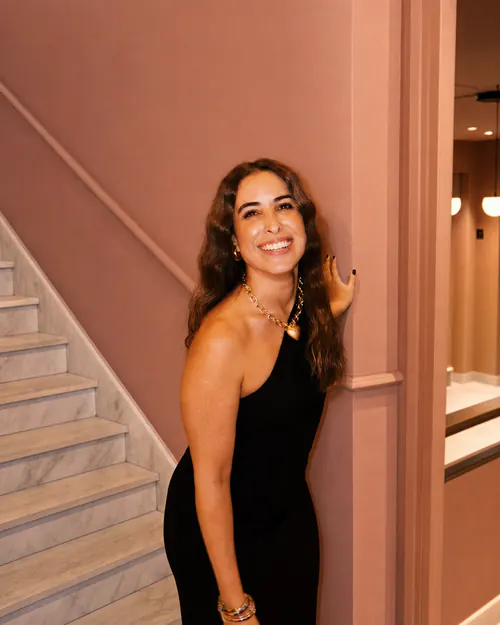 Isa standing next to a marble staircase, wearing a black dress